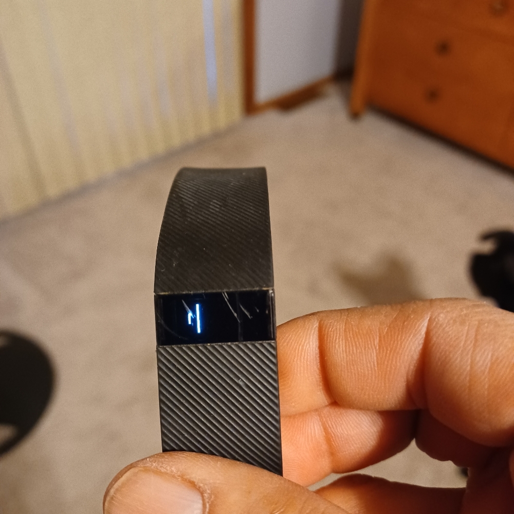 FitBit Black. Includes charger. Reports steps, miles and calories.
